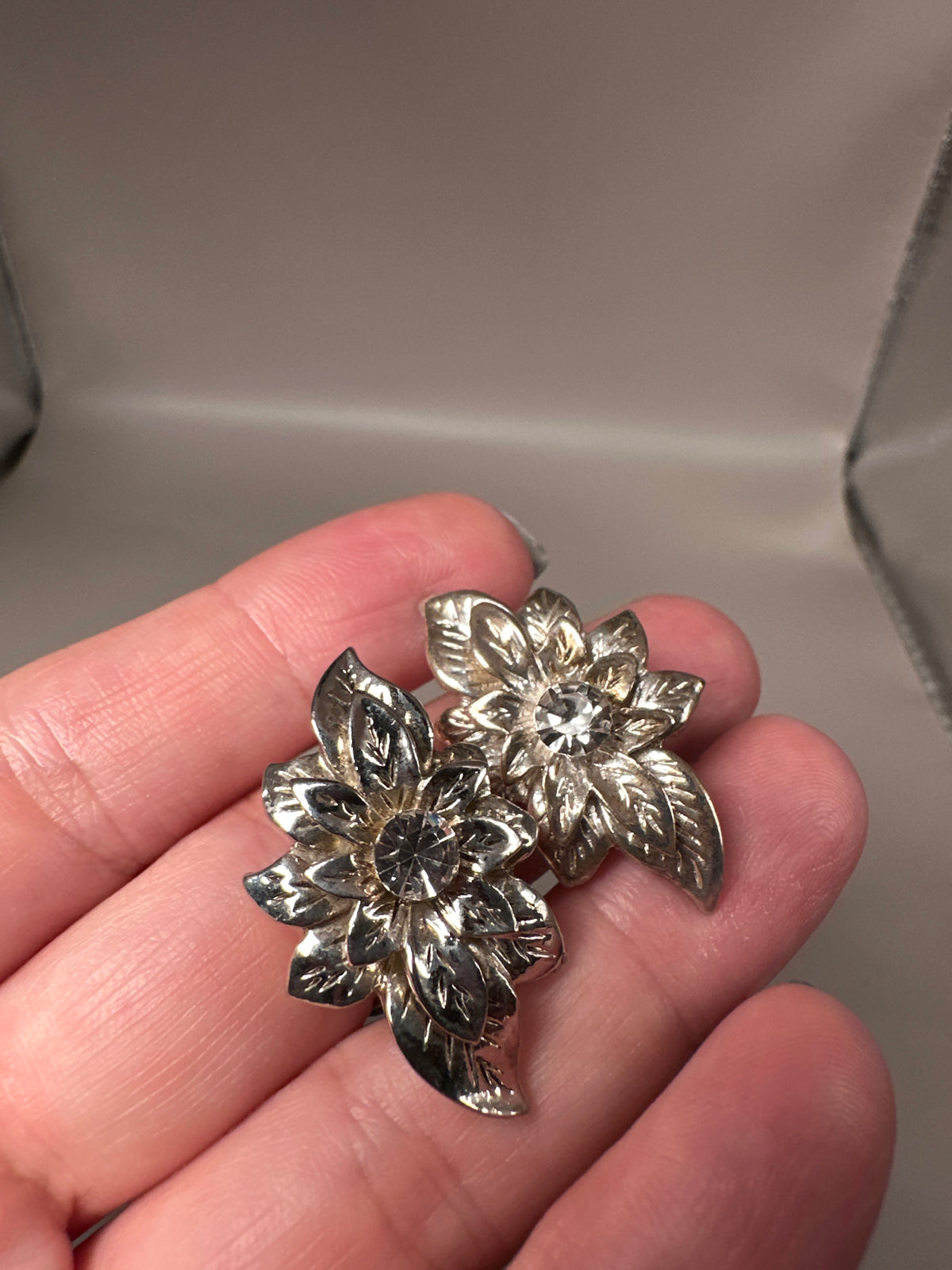 Single earring held in hand for scale showing size and dimensional foliate construction detail