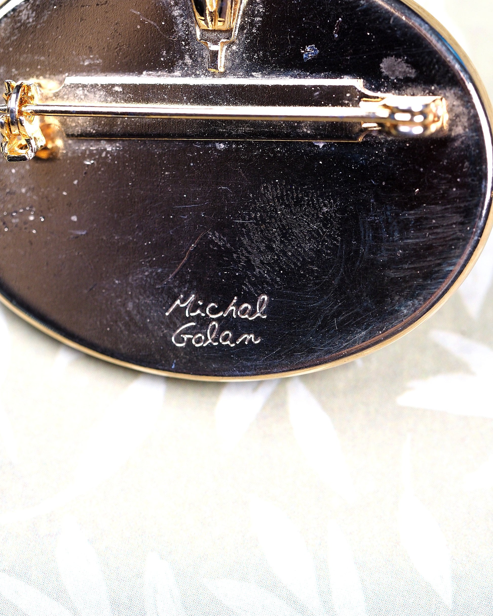 Close-up of engraved Michal Golan signature on black enamel reverse