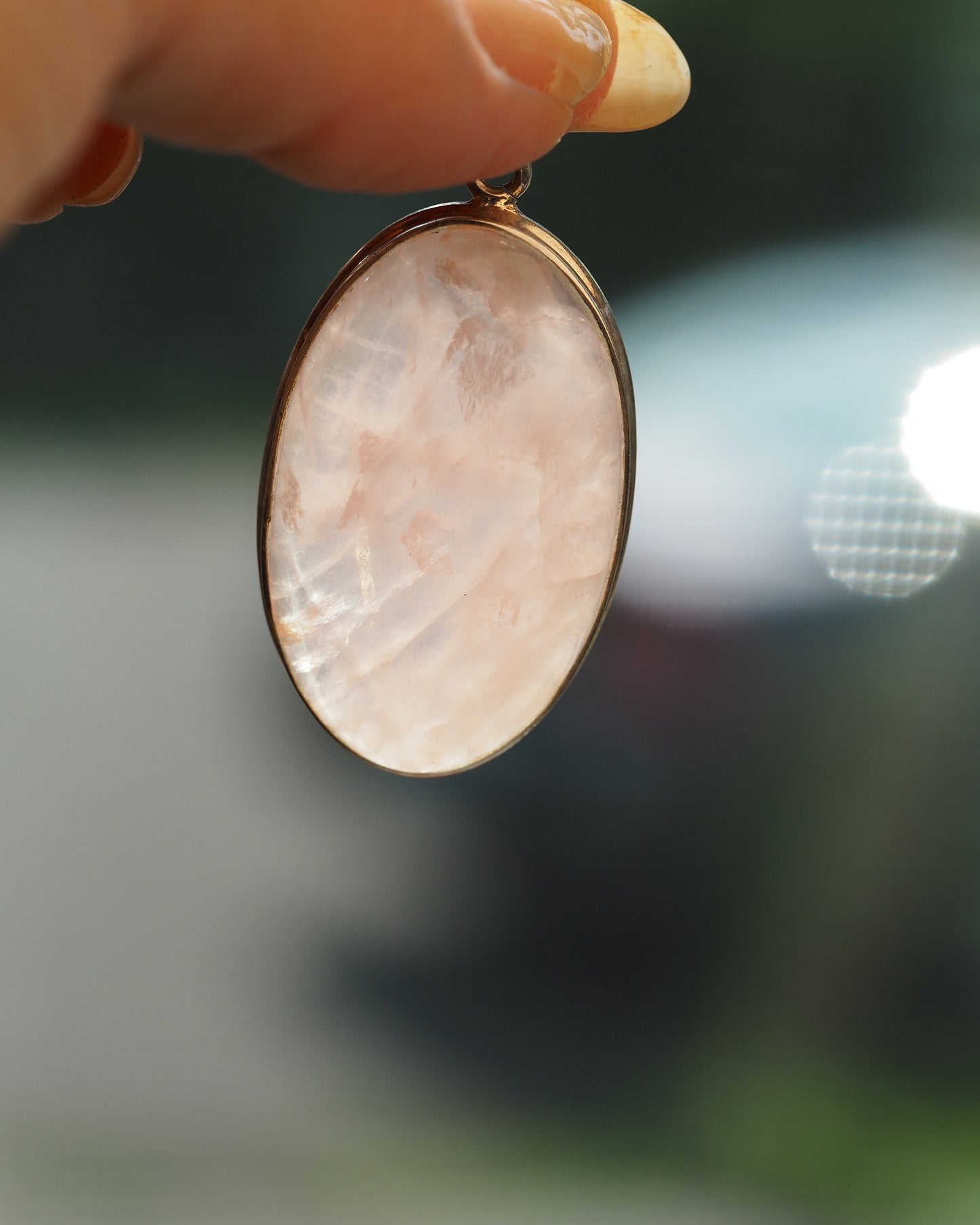 close-up of rose quartz pendant showing milky pink translucence and natural inclusions in silver bezel