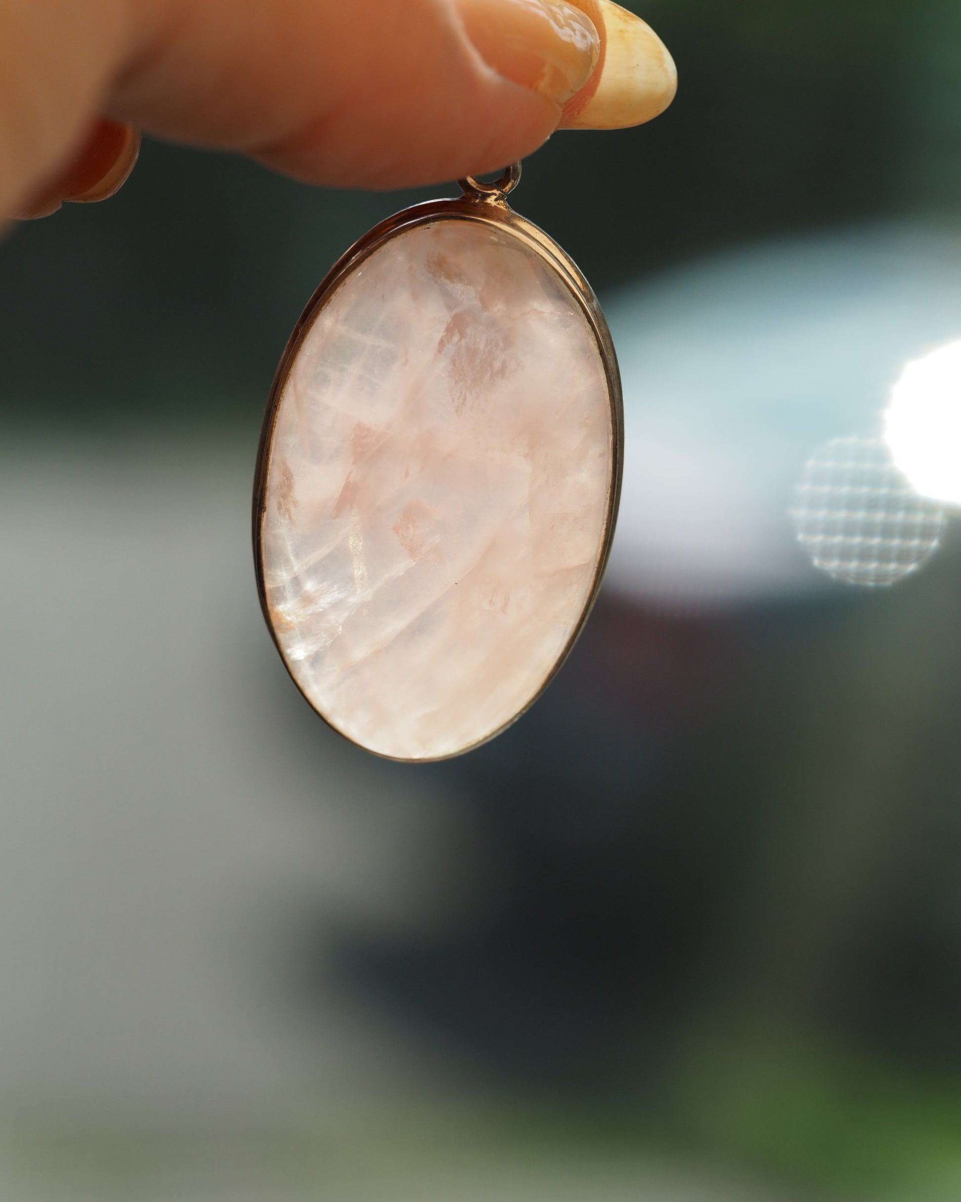 close-up of rose quartz pendant showing milky pink translucence and natural inclusions in silver bezel