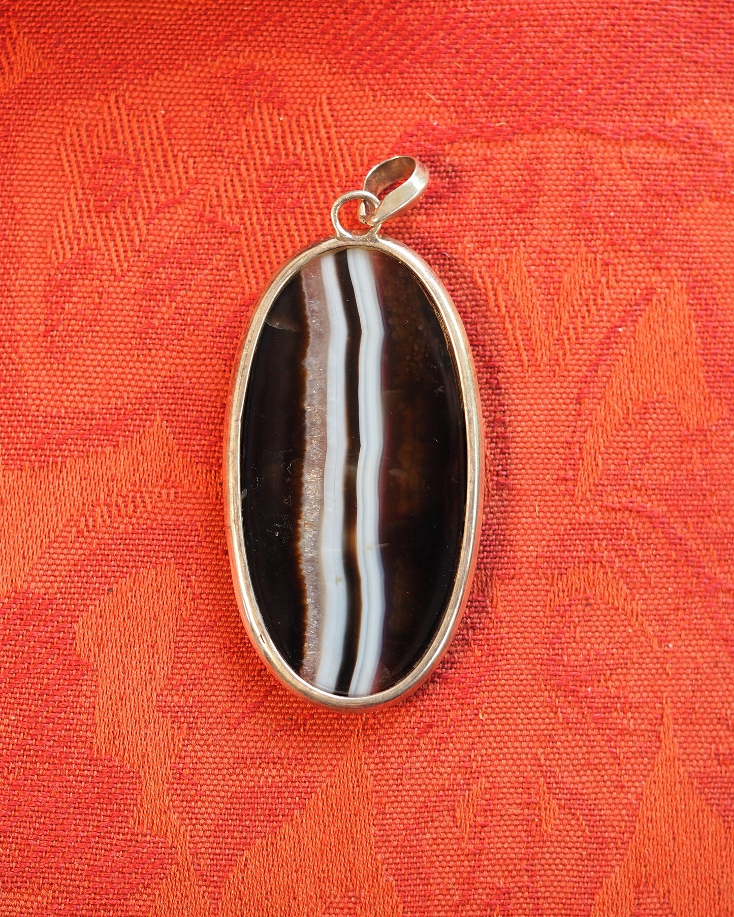 Back view of silver-bezeled banded agate pendant showing clean setting and slide bail