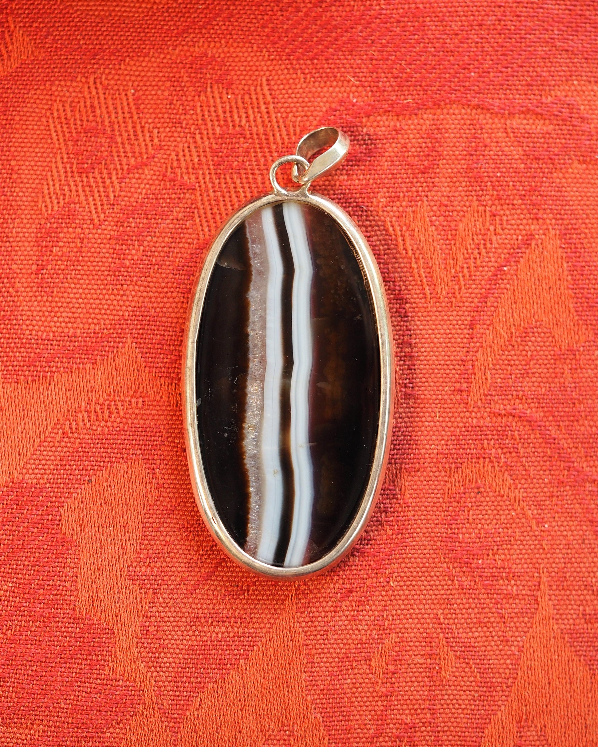 Back view of silver-bezeled banded agate pendant showing clean setting and slide bail
