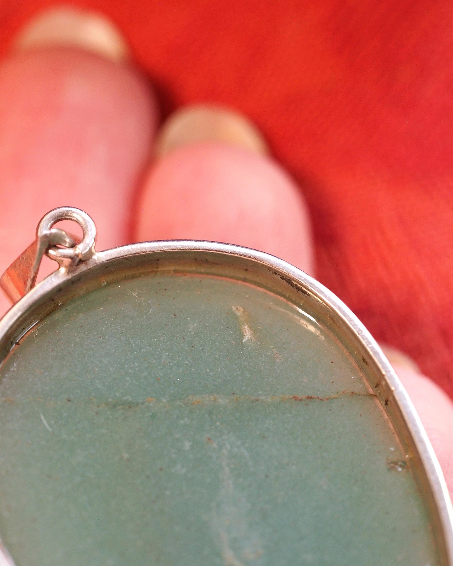 Close-up of sterling silver slide bail attachment showing spring tension mechanism and bright finish at top of pendant