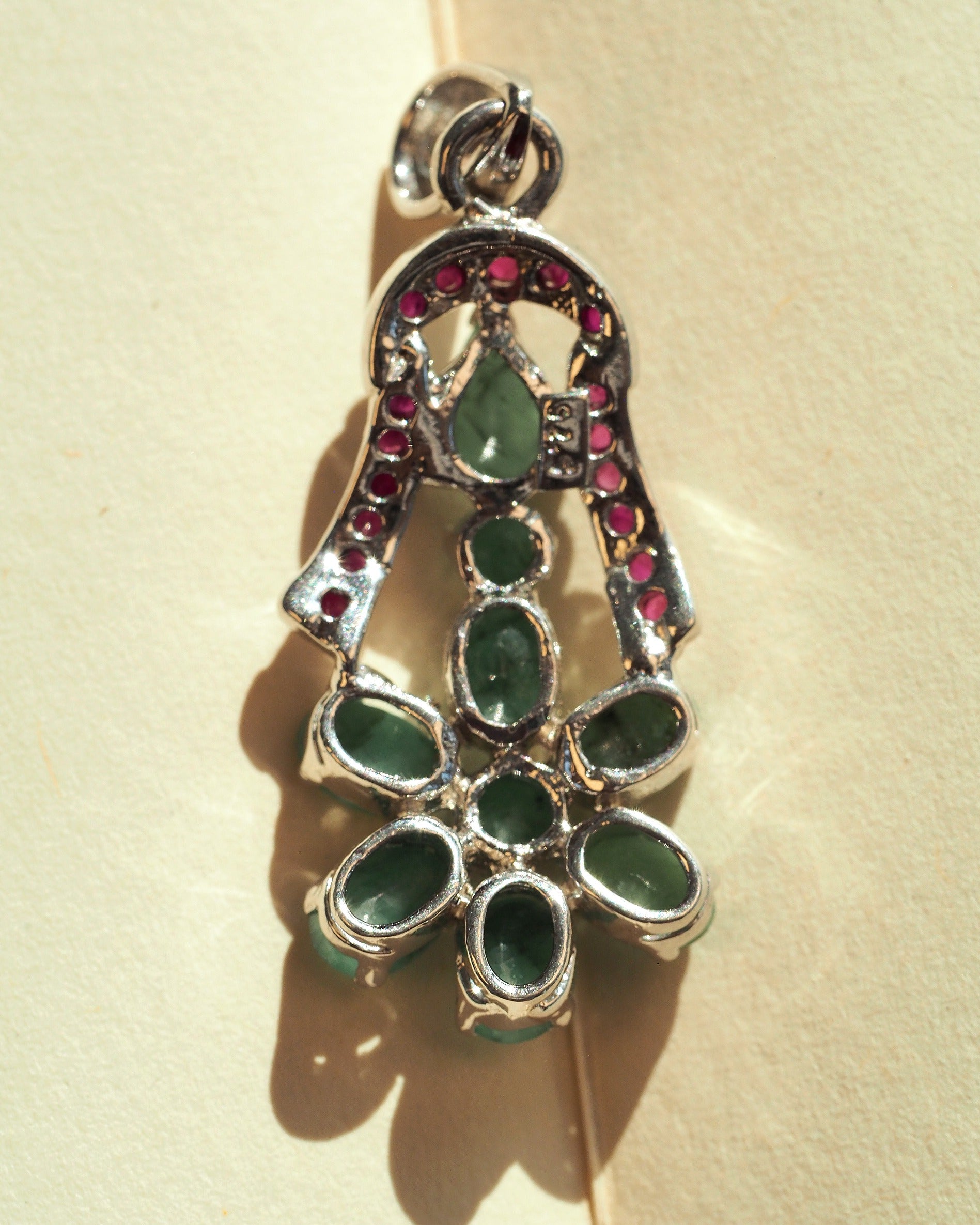 Back view of sterling silver green and red stone flower pendant with slide bail visible