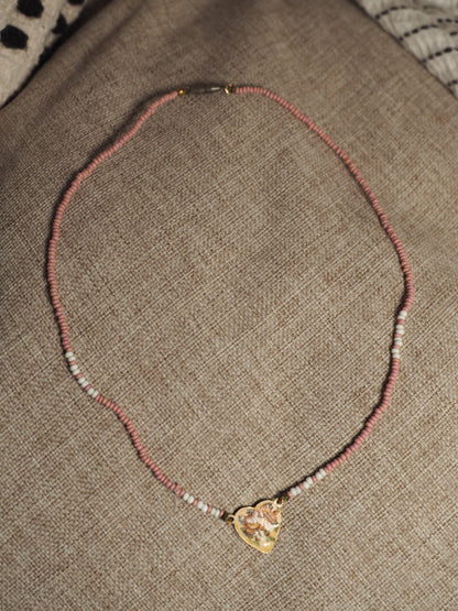 Full 16-inch necklace laid in a circle showing pink and white beaded strand with brass heart charm