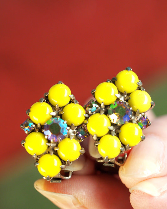 Close-up of yellow glass cabochons and Aurora Borealis rhinestones in gold-tone pronged settings held in hand