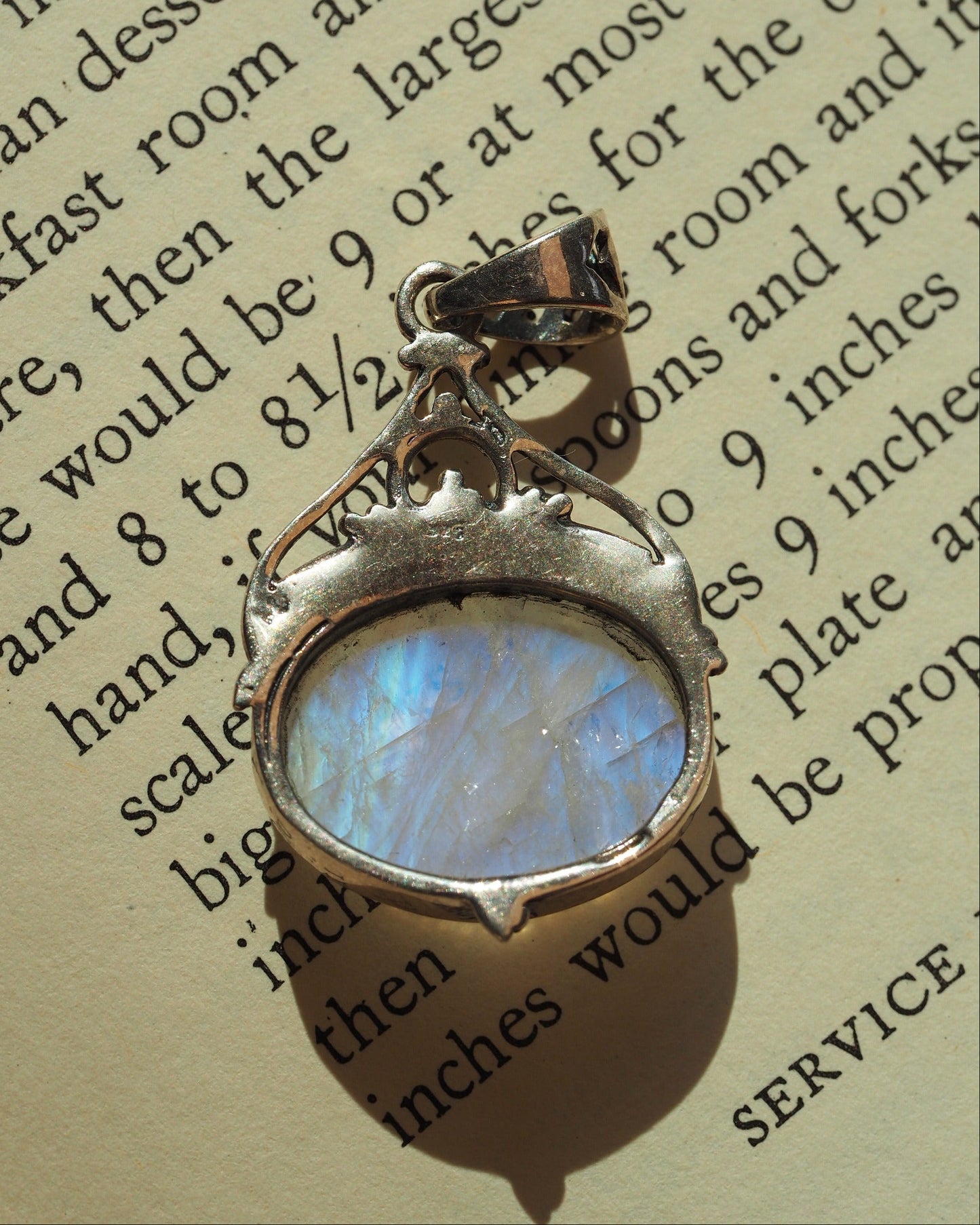 Close-up of faceted rainbow moonstone in sterling bezel, showing blue adularescence and rope-texture band