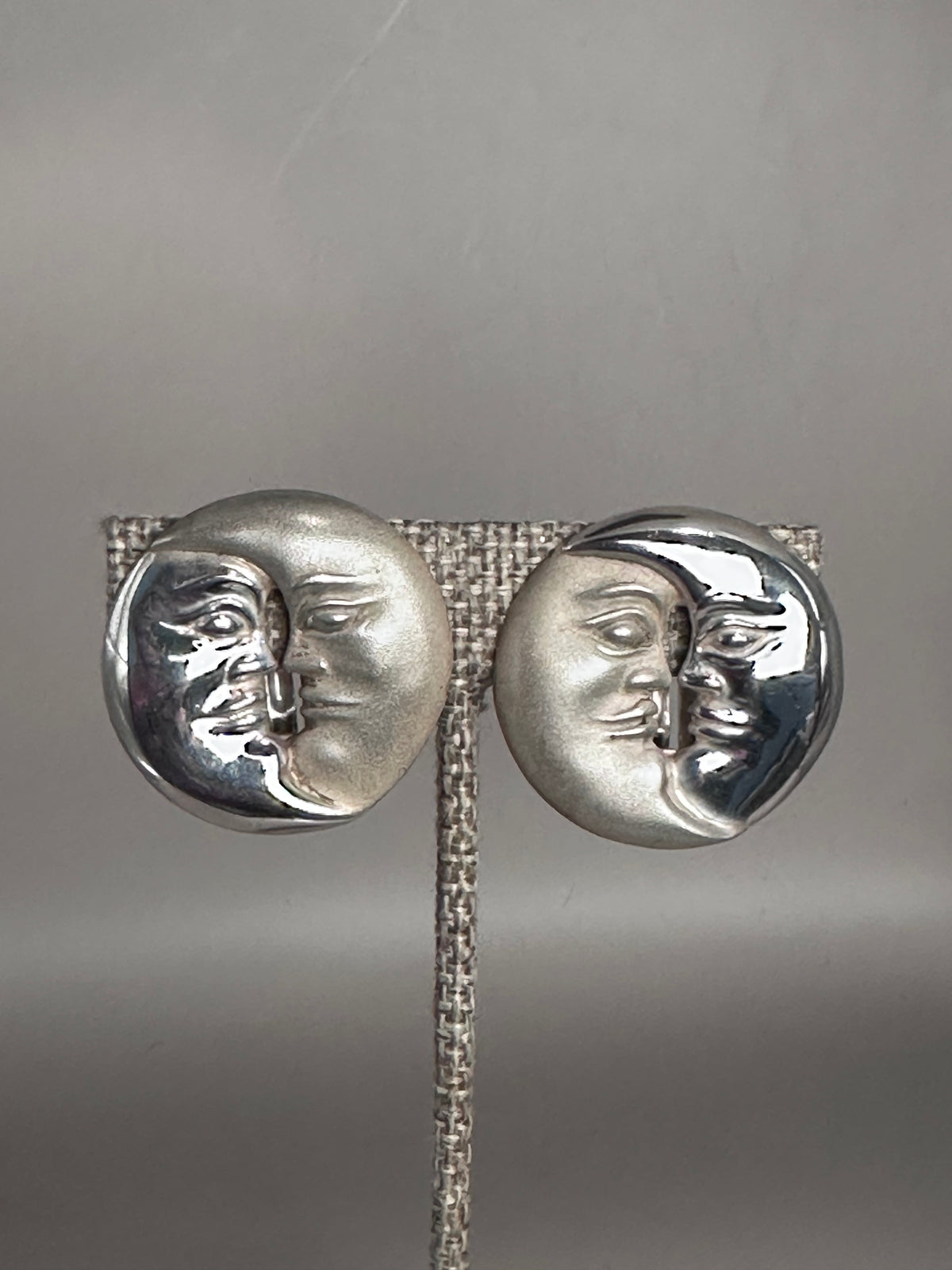 sterling silver Taxco sun and moon clip earrings front view, showing overlapping sculptural faces with contrasting matte and polished finishes