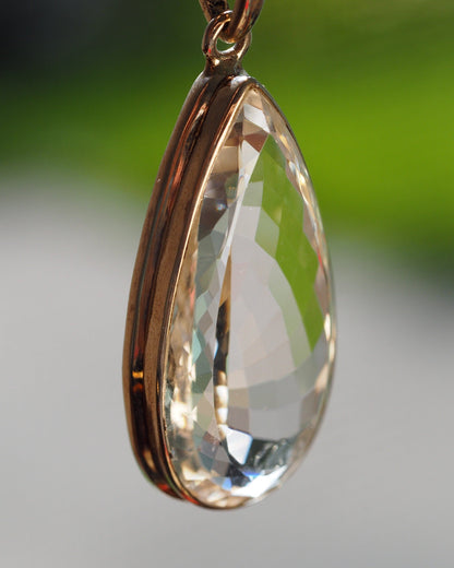 Sterling silver faceted clear stone pendant, side angle showing closed bezel and dimensional cuts