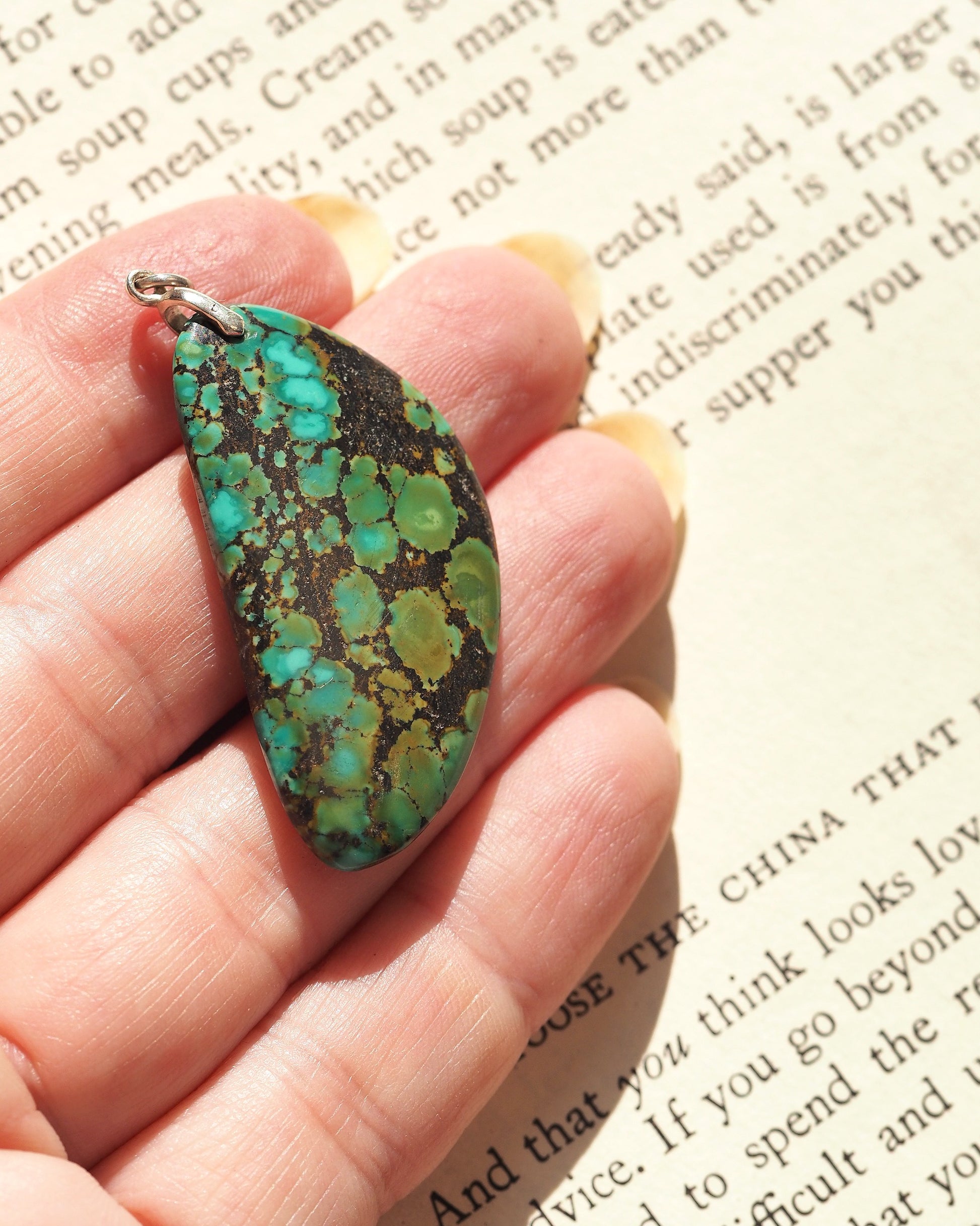 Sterling silver blue-green matrix stone pendant held in hand for scale, showing 1 7/8 inch teardrop shape