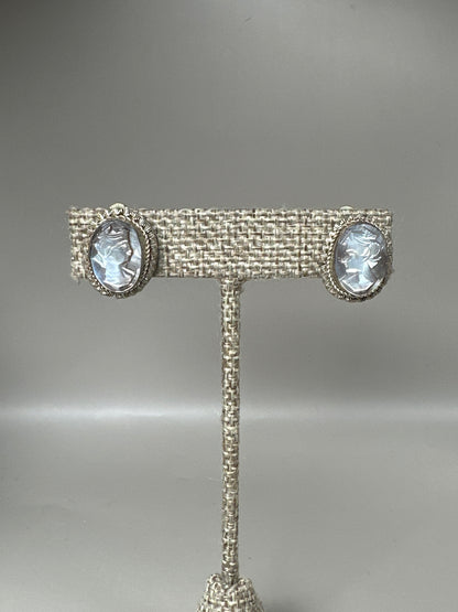 800 silver mother-of-pearl cameo clip earrings with carved profiles and notched bezel frames, front view on stand