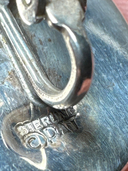 Macro close-up of ©PAT STERLING hallmark stamped on earring back