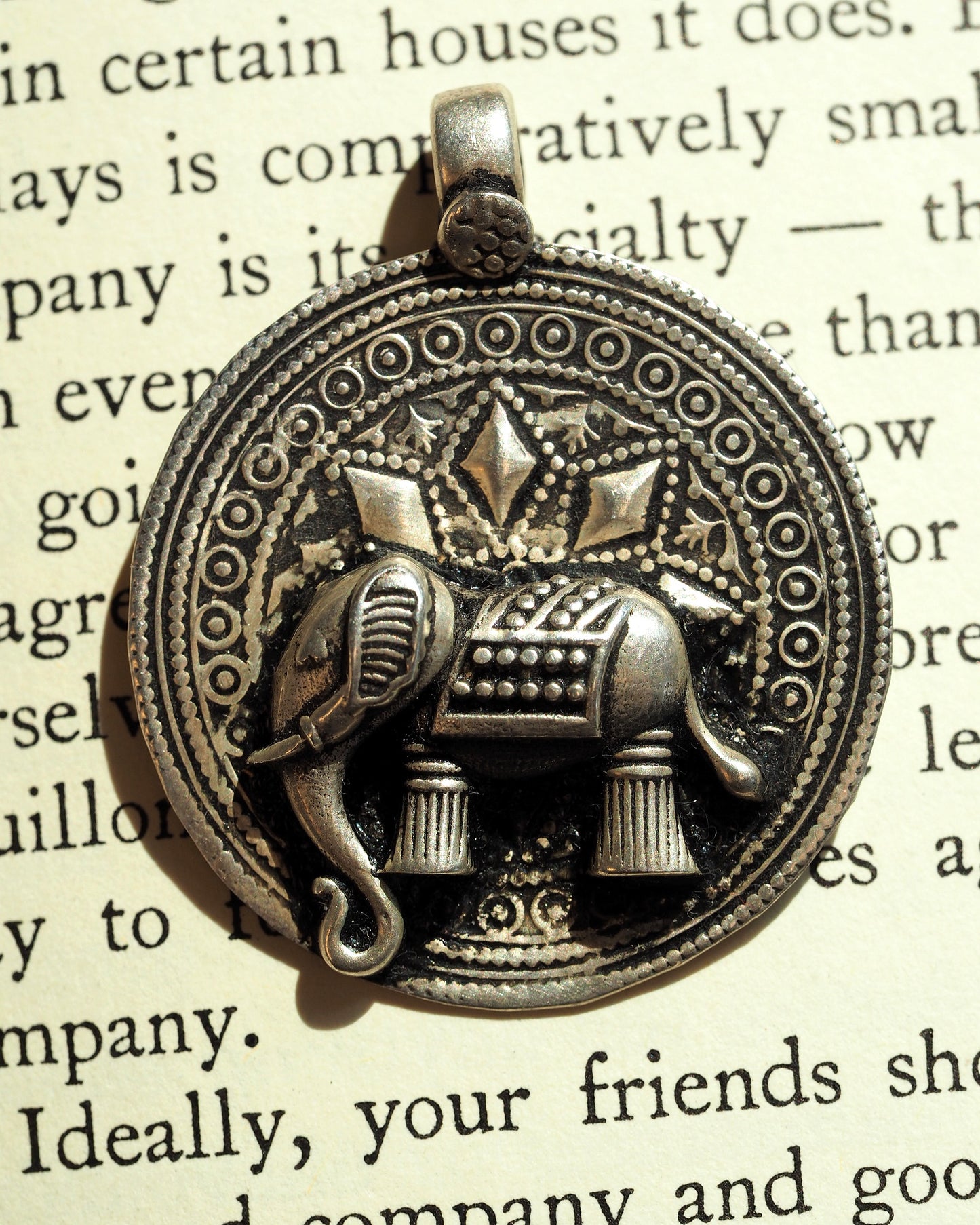 Close-up of elephant motif with diamond shapes and textured blanket detail on silver pendant