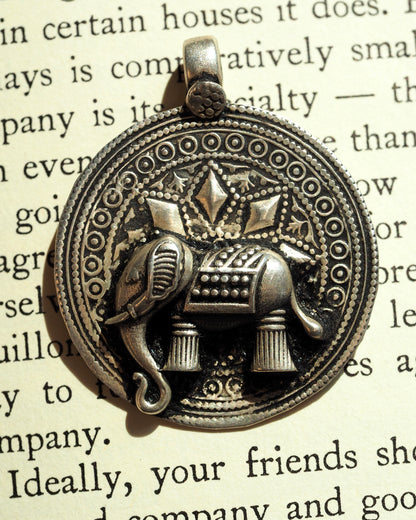 Close-up of elephant motif with diamond shapes and textured blanket detail on silver pendant