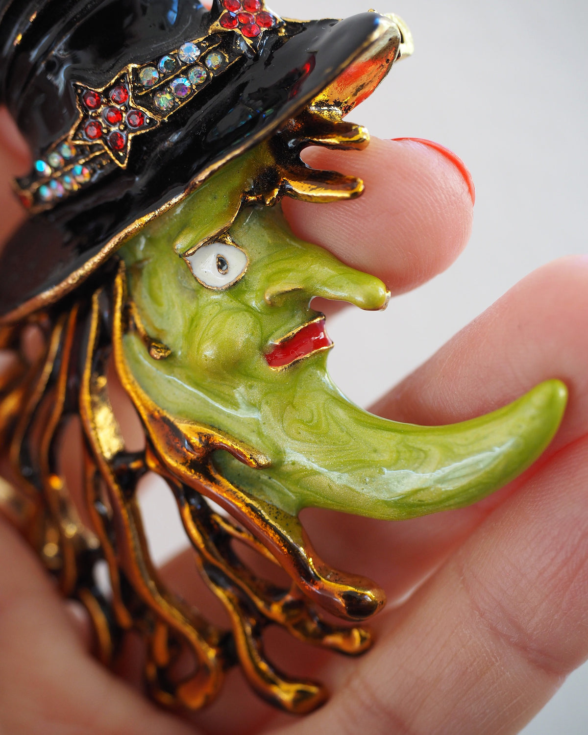 Close-up of green enamel witch face and gold-tone fringe hair