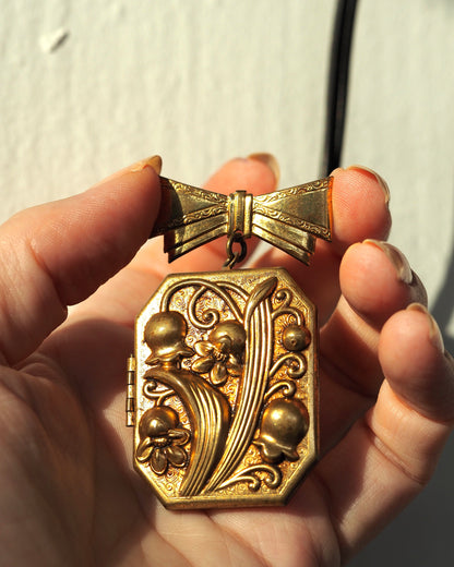 Locket brooch held in hand for scale, showing size relative to fingers