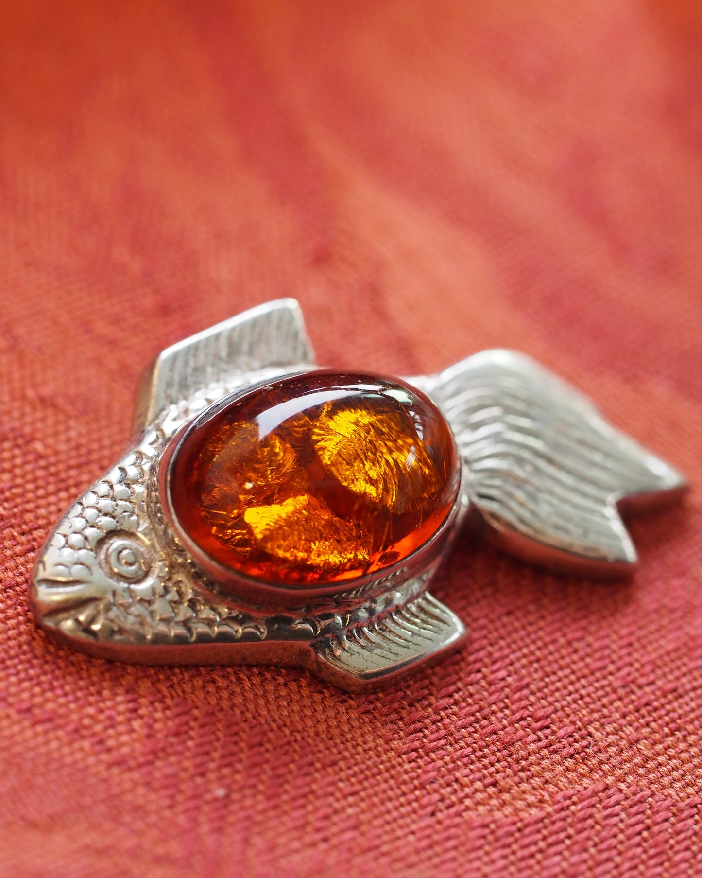 Close-up of amber cabochon and detailed scale relief on the fish body