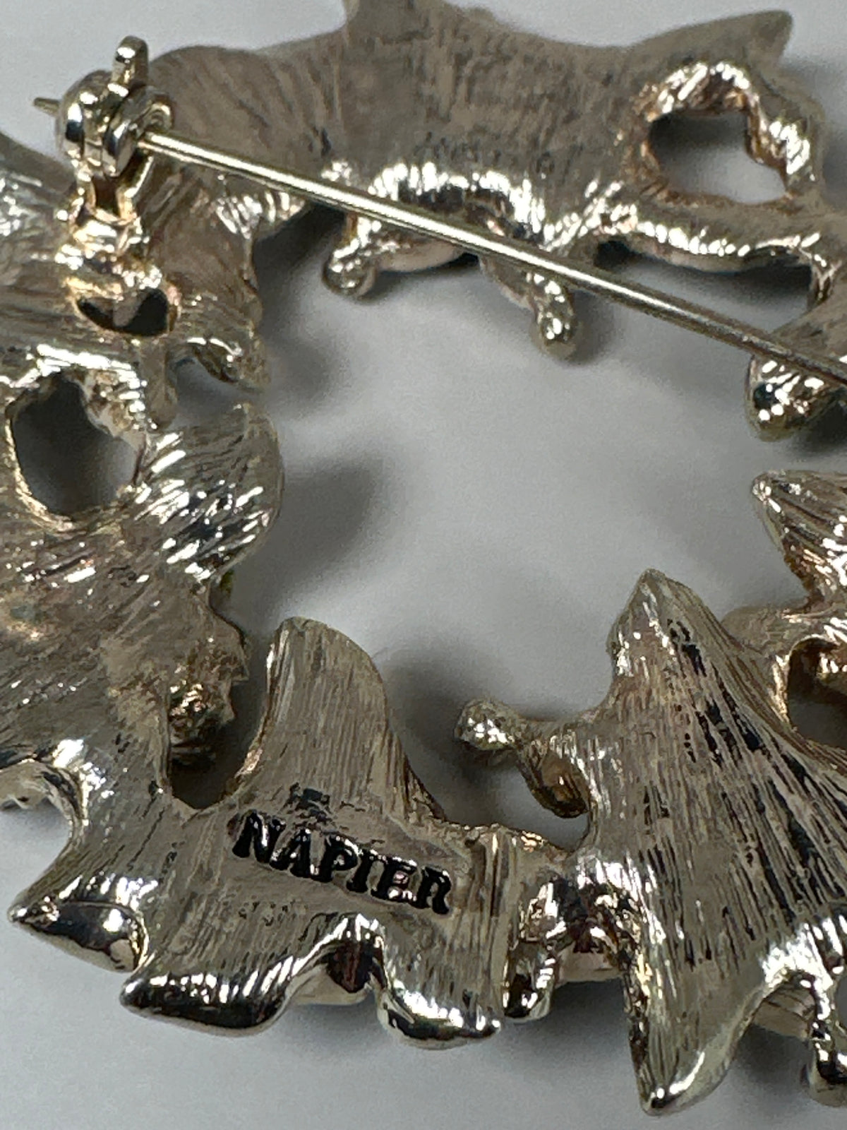 Close-up of NAPIER signature stamp and pin clasp on the reverse of gold-tone enamel wreath brooch