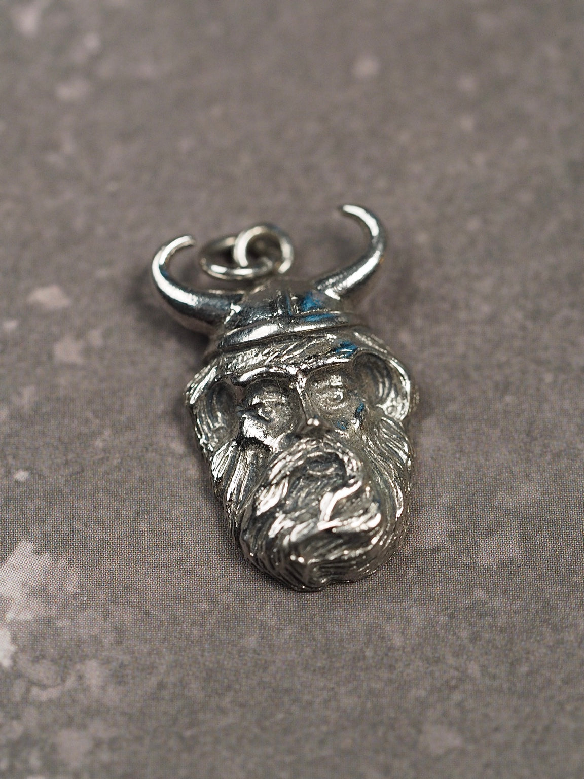 Angled view of vintage Kinney sterling silver Viking head charm pendant