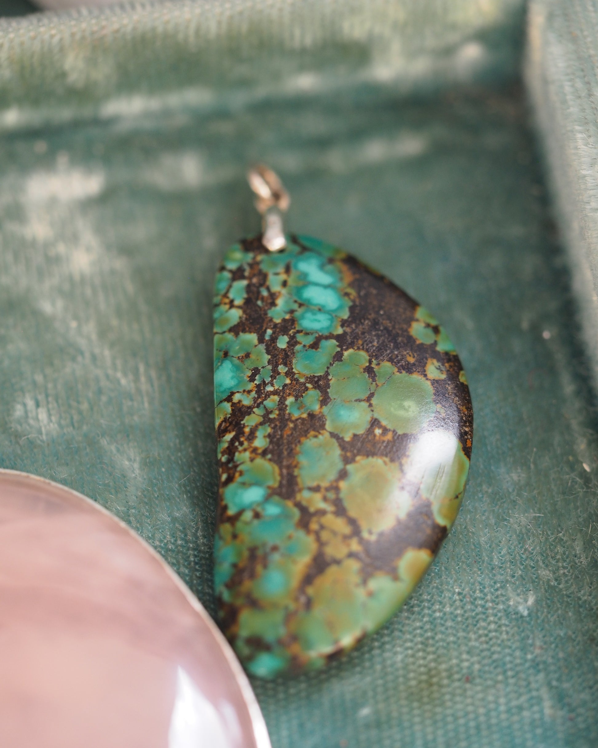 Close-up of polished blue-green matrix stone showing turquoise-color and chartreuse pattern in dark matrix