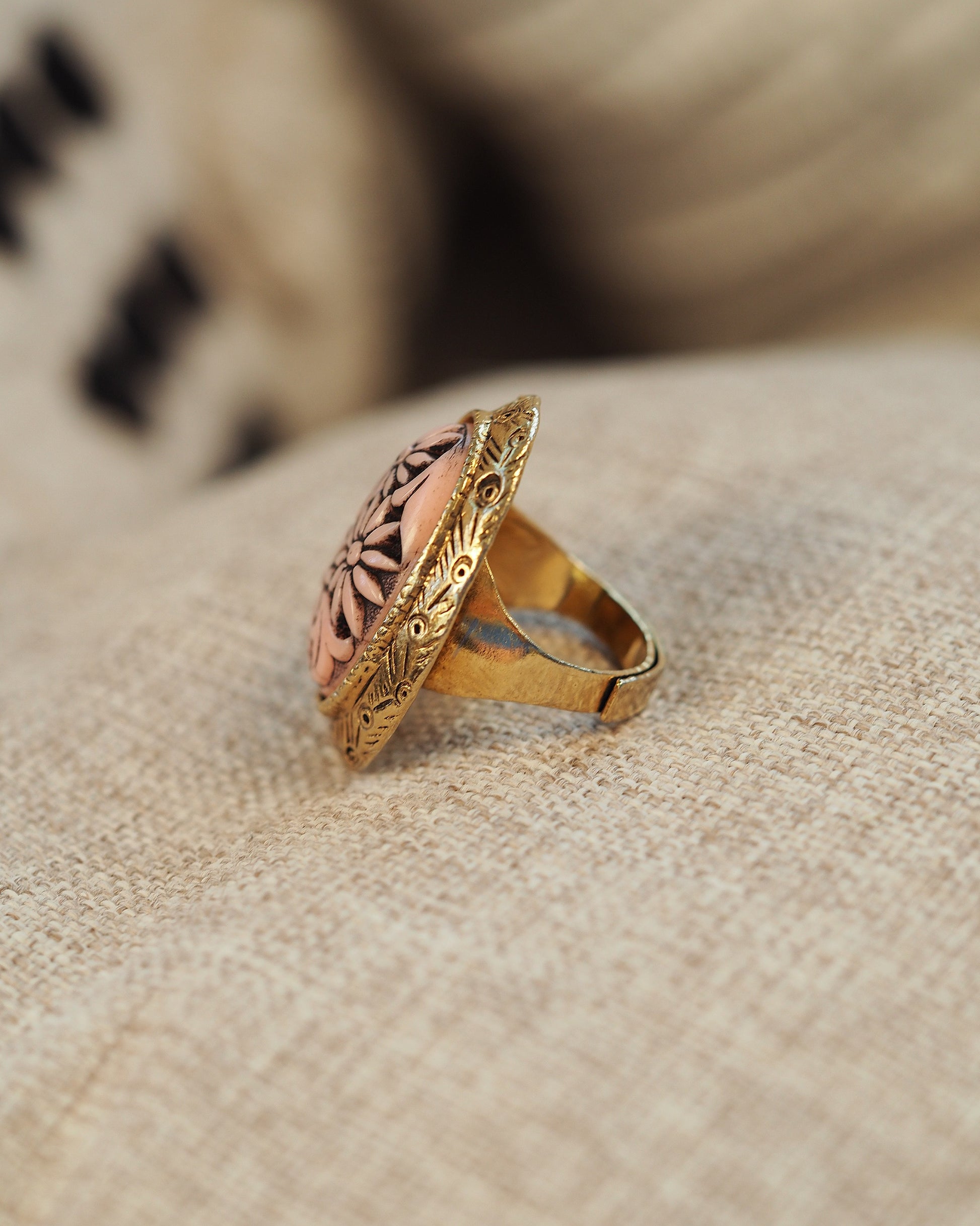 Side view of adjustable ring showing high-profile carved resin cabochon and ornate gold-tone setting
