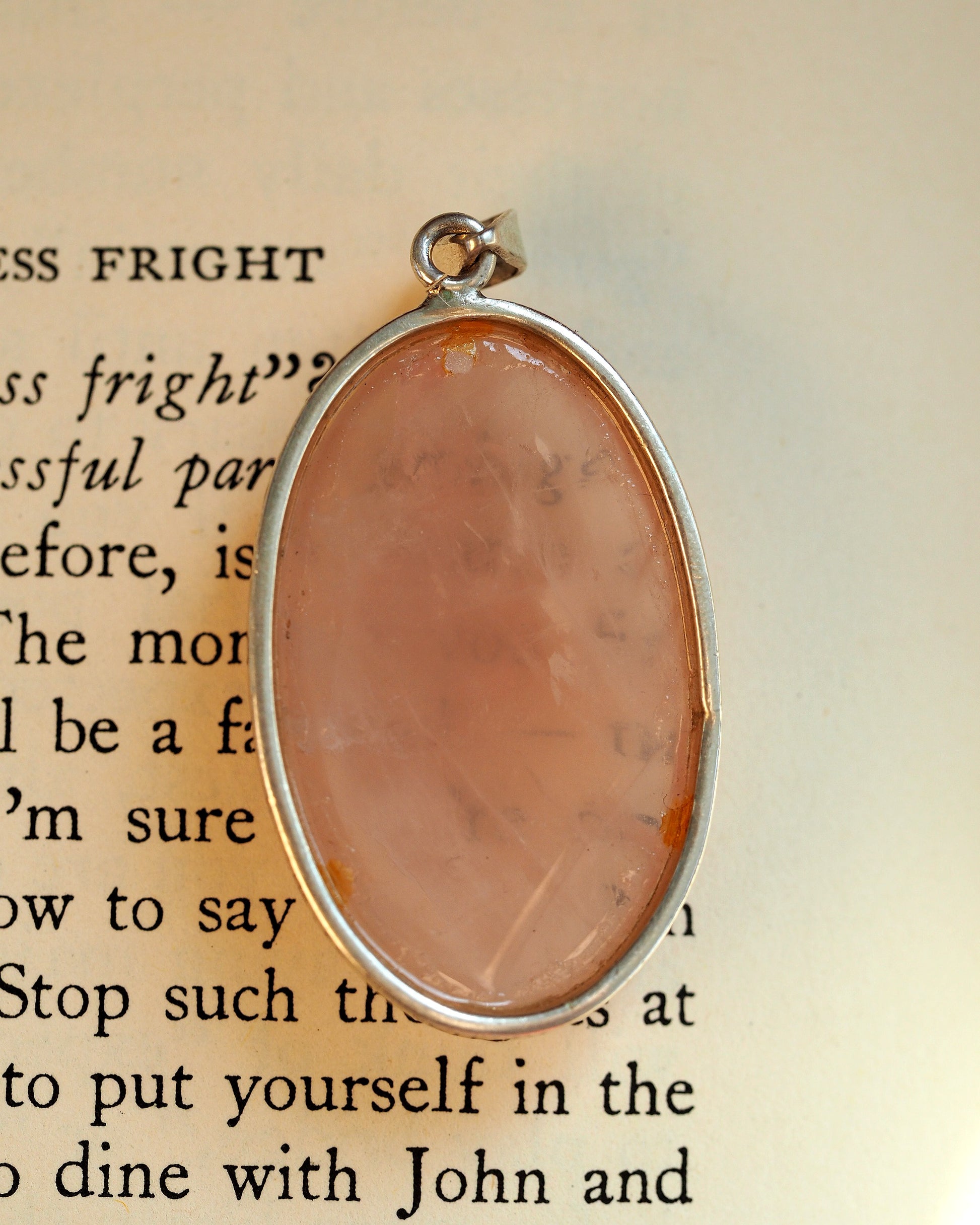 back view of rose quartz pendant showing sterling silver bezel and curved bail