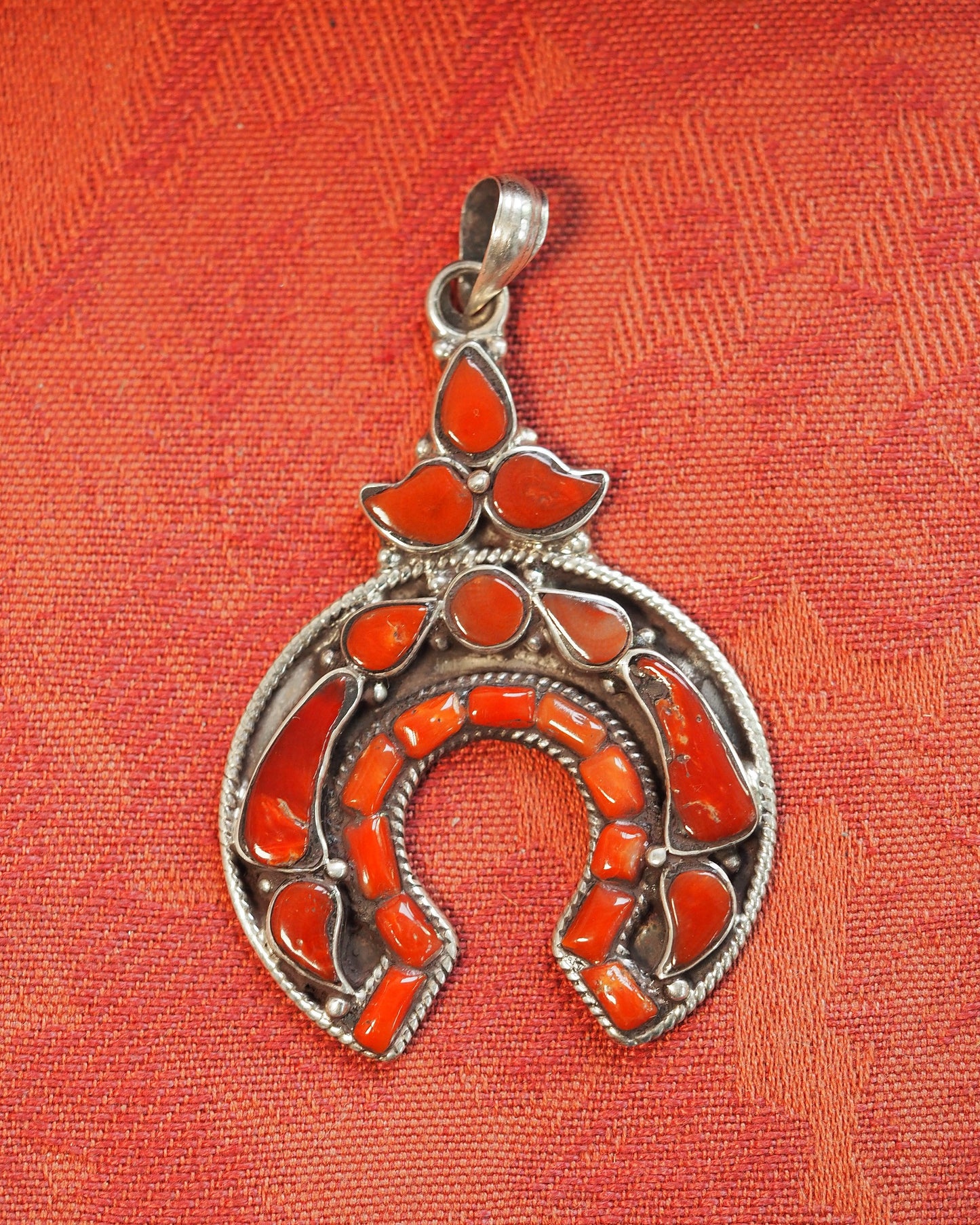 Red coral naja pendant on orange fabric, full front view showing twisted rope bezels and coral cabochons