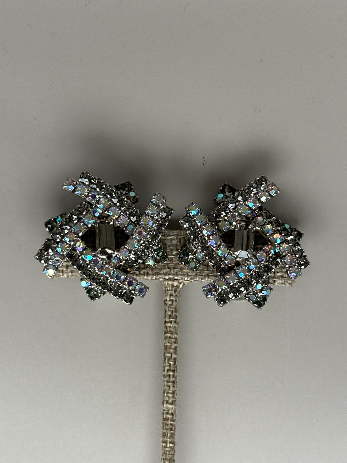 Clip earrings front view on stand showing symmetrical starburst design with AB crystals surrounding smoky centers