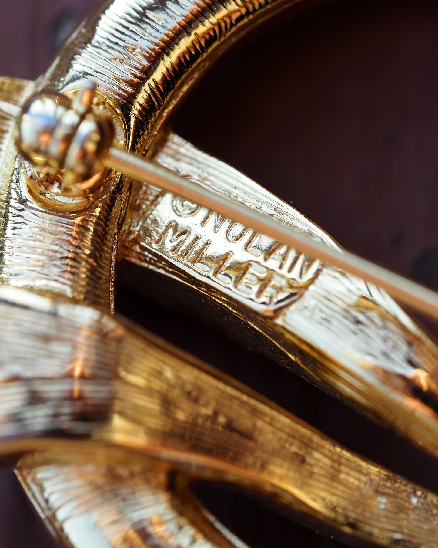 Close-up of the Nolan Miller signature stamp on the pin stem clasp hardware