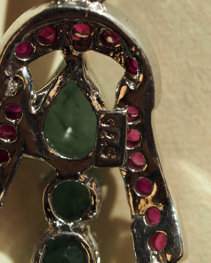 Detail of openwork basket with red accent stones and a green teardrop cabochon at center