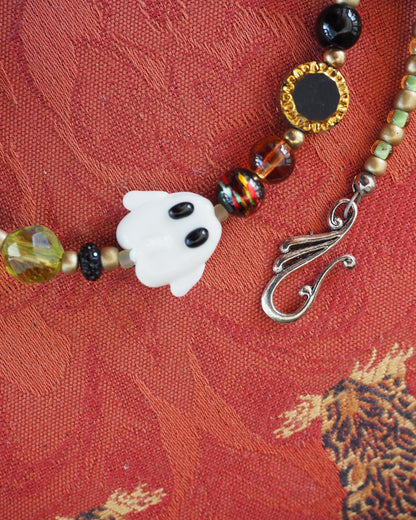 Detail view of white ghost bead with black eyes, multicolor blown glass beads, and decorative silver-tone hook clasp