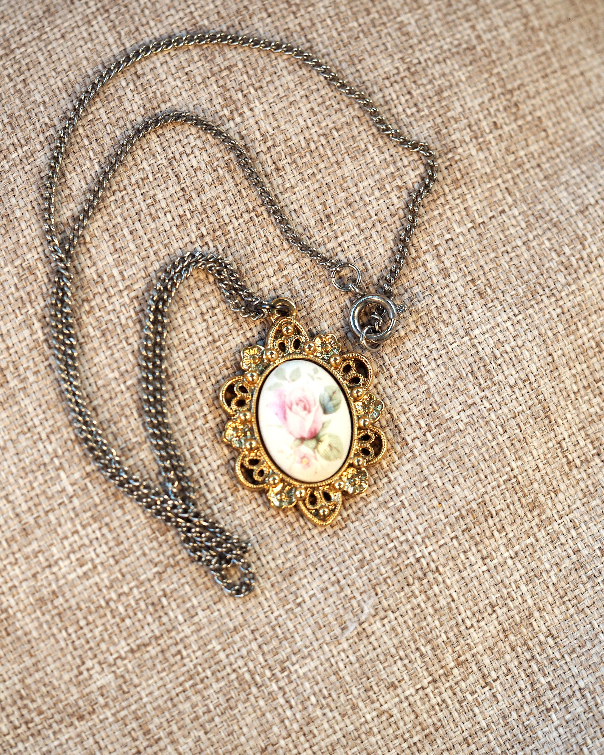 Close-up of silver-tone chain with spring ring clasp attached to gold-tone pendant bail