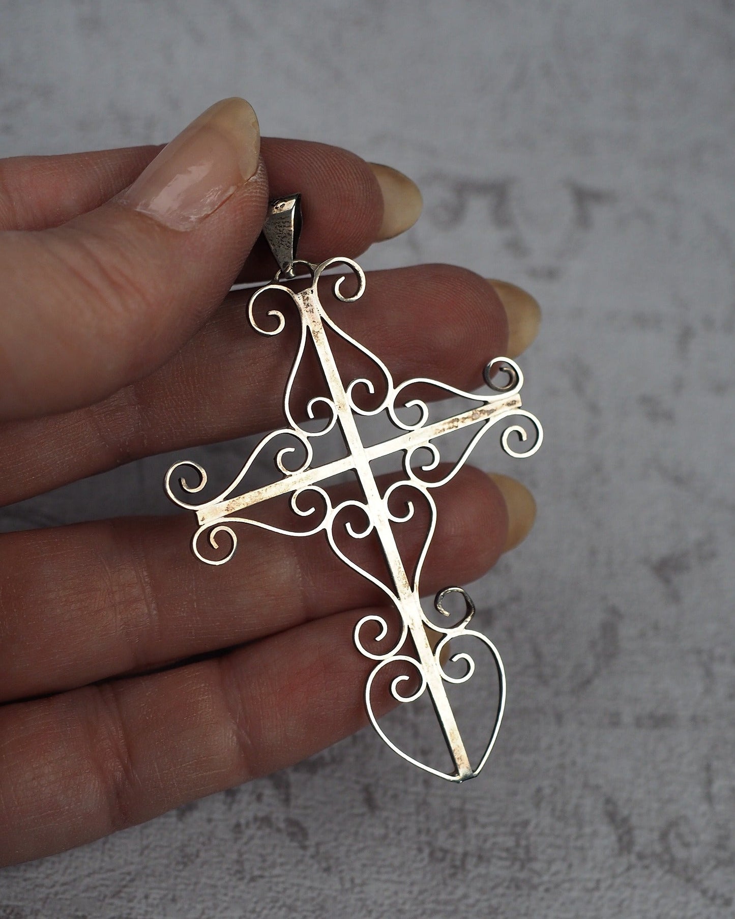 Large Taxco sterling silver cross pendant held in hand for scale