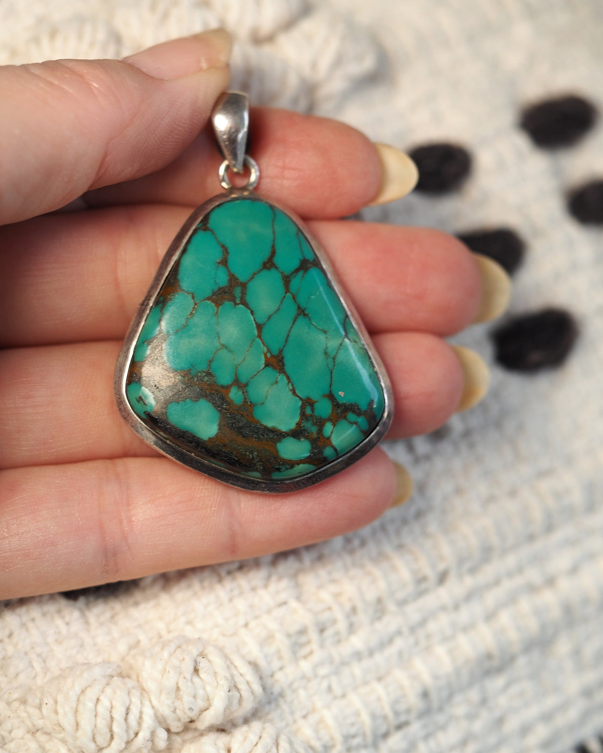 Sterling silver blue stone pendant held in hand for scale, 2.25 inches tall
