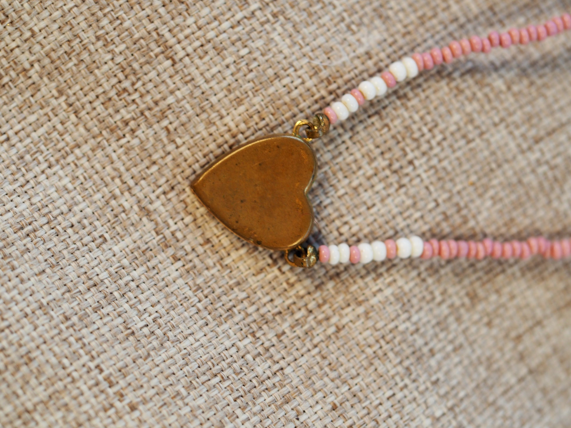Reverse side of the half-inch brass heart charm showing patinated undecorated surface